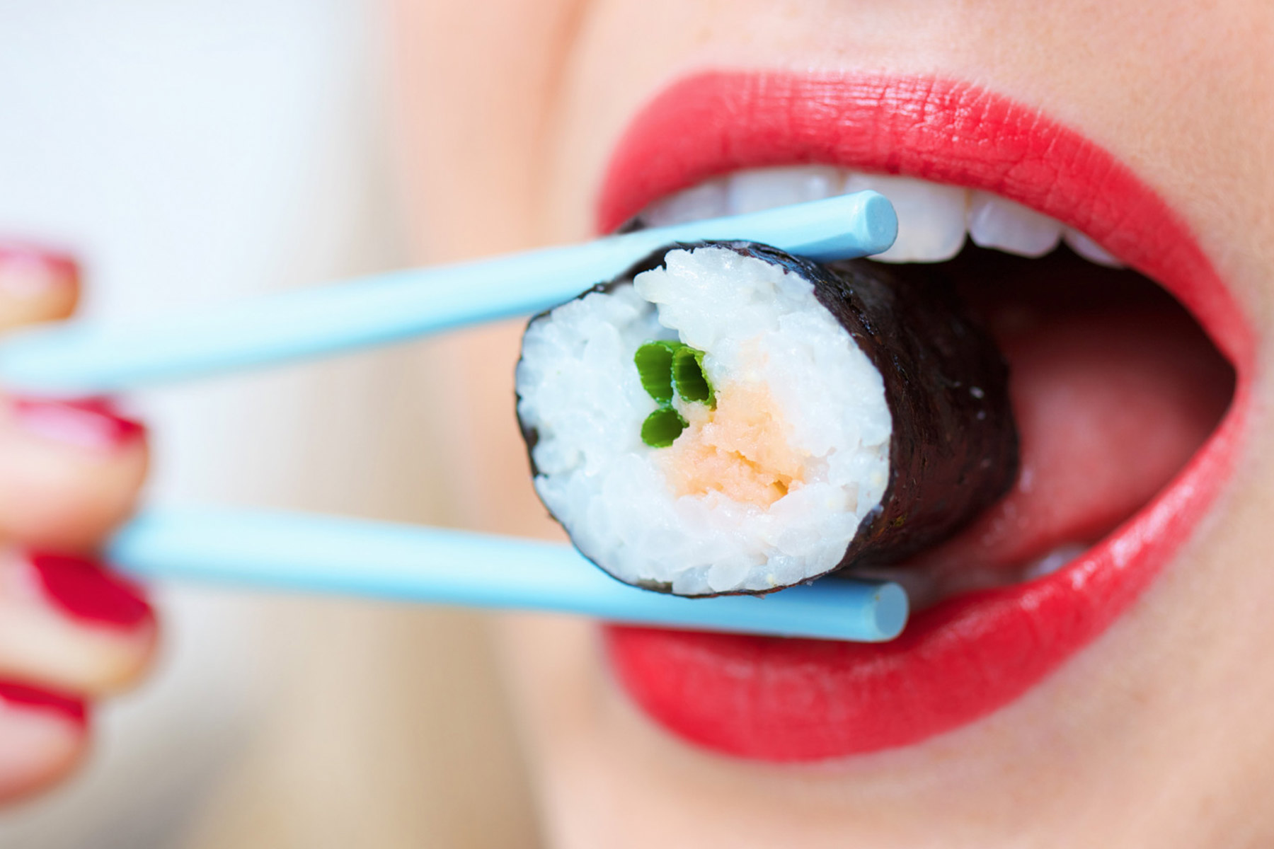 Девушка есть суши. Суши во рту девочки. Девушка ест роллы.